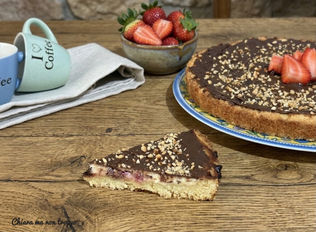 Una fetta di crostata alla ricotta con Nutella e granella di nocciole su un tavolo di legno.