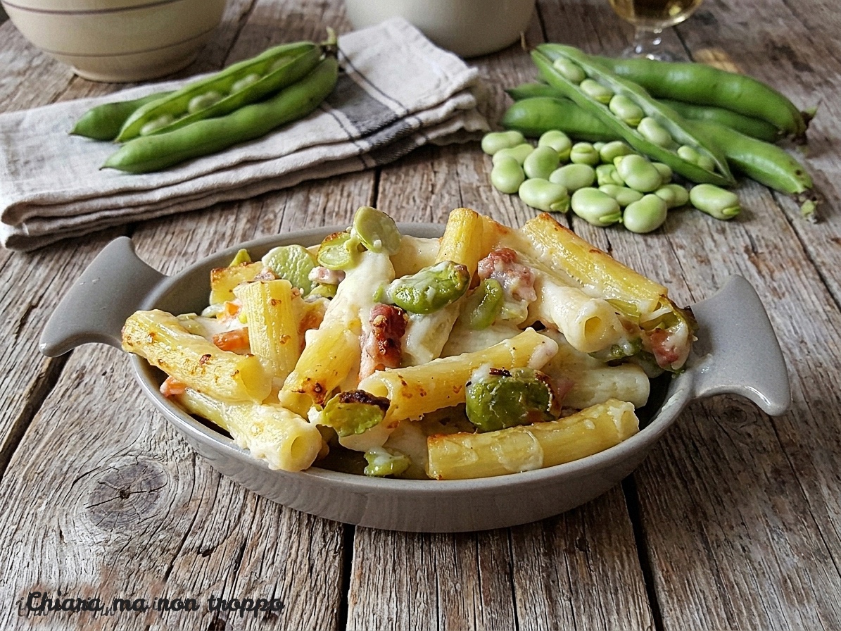 Una porzione invitante di pasta al forno condita con fave fresche e cubetti di pancetta.