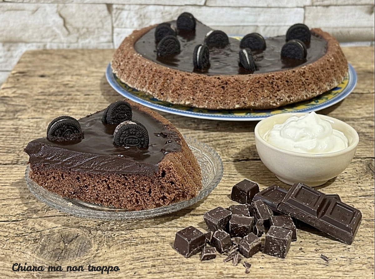 Vista dall'alto di una torta crostata morbida al cacao farcita con ganache lucida al cioccolato fondente e decorata con biscotti scuri farciti e spezzati.