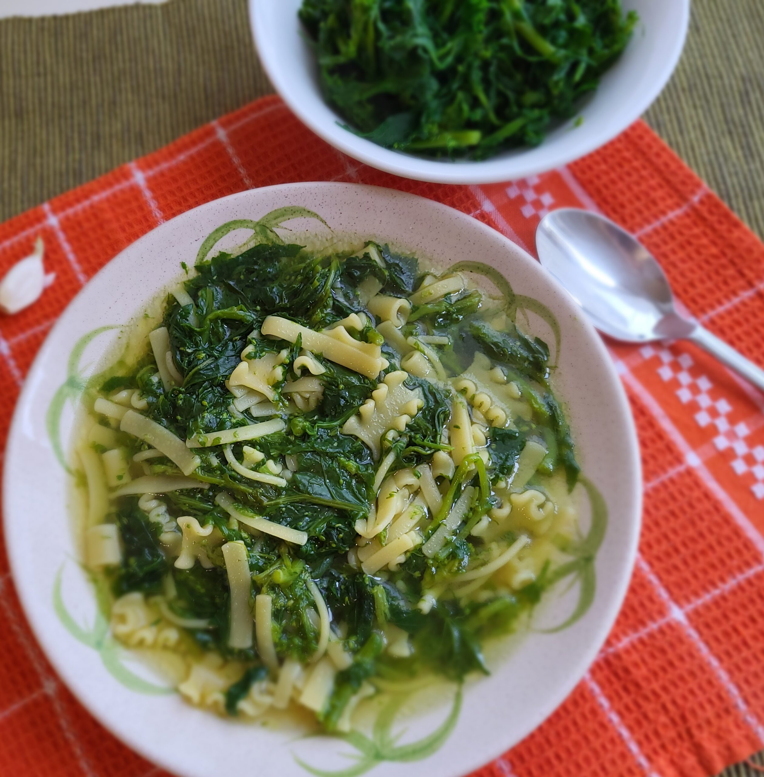 Piatto di pasta con cime di rape in brodo servito in tavola.
