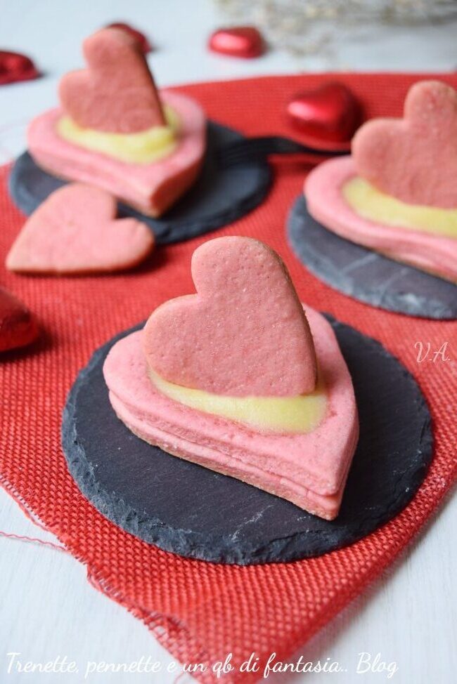 Biscotti rosa con cuore di crema, impasto friabile e senza burro, un mix di dolcezza e semplicità! ci regalano un’esplosione di dolcezza ad ogni morso.